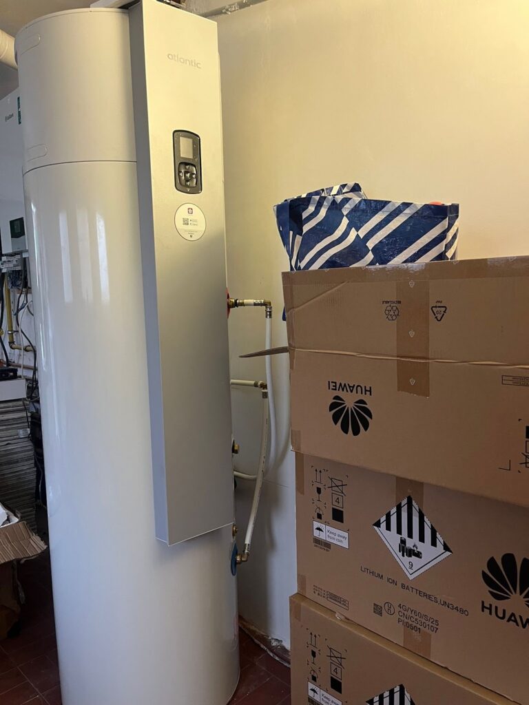 Witte warmtepompboiler in een berging, naast de dozen van de installatie