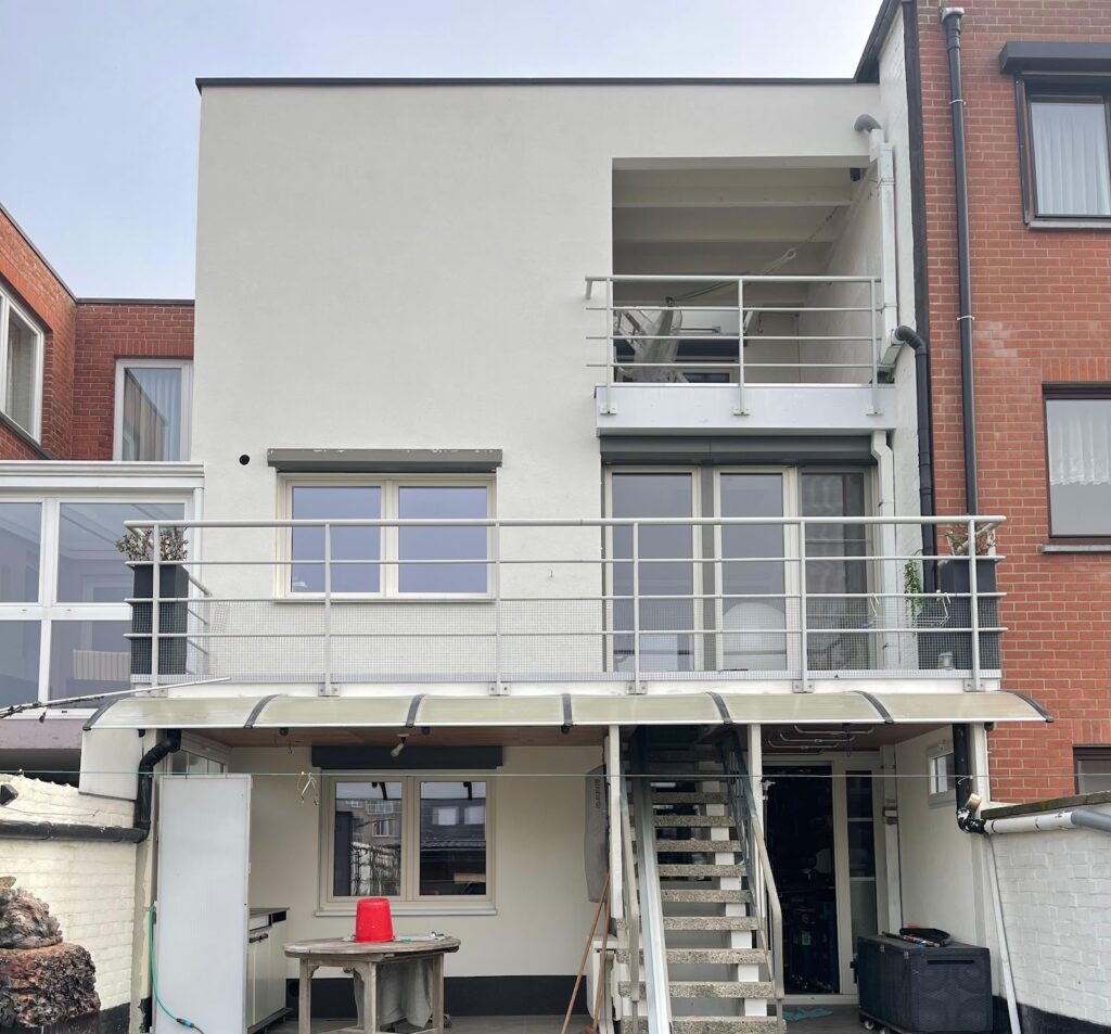 Witte achtergevel met balkons na de renovatie