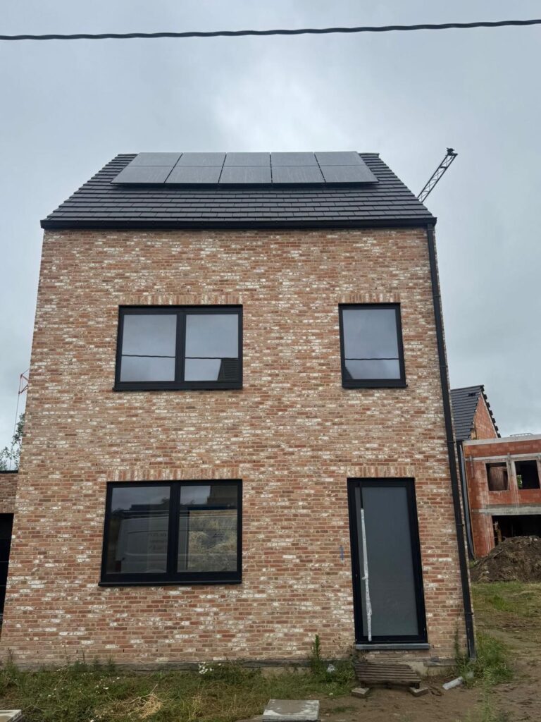 Smalle nieuwbouwwoning in rode baksteen met zwarte zonnepanelen op het dak